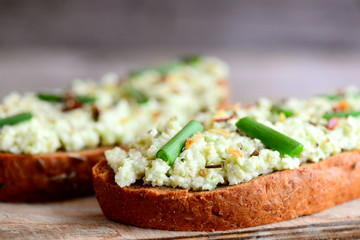 Simple open guacamole sandwiches with spices mix and fresh green onions. Avocado guacomole sandwiches recipe. Closeup