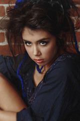 Fototapeta premium Young cute woman posing against a brick wall