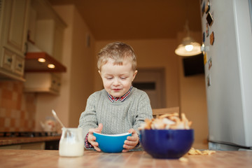 Child holding a bowl while sitting at kitchen