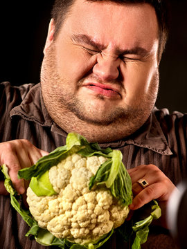 Diet fat man eating healthy food. Healthy breakfast with vegetables cauliflower. Male trying to lose weight. Concept on black background. Doctor makes patient switch to healthy food.