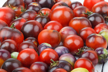 Different tomatoes on the white wooden background