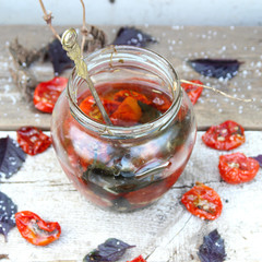 Dried tomatoes and purple basil on a white wooden background.