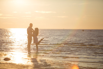 Fototapeta premium A young couple in love, on the shore of the Bay at sunset