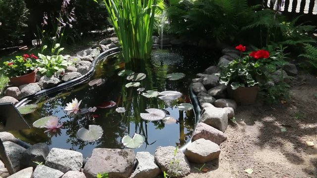 Water pond with fountain at the garden with flowers