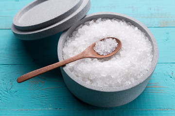 Sea salt in an stone bowl with small wooden spoon on a blue wooden table