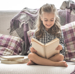 little girl reading book on sofa