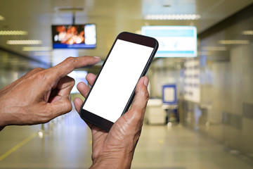 Man hand holding and using mobile,cell phone,smart phone with isolated screen with blurred of corridor inside the metro station for background.