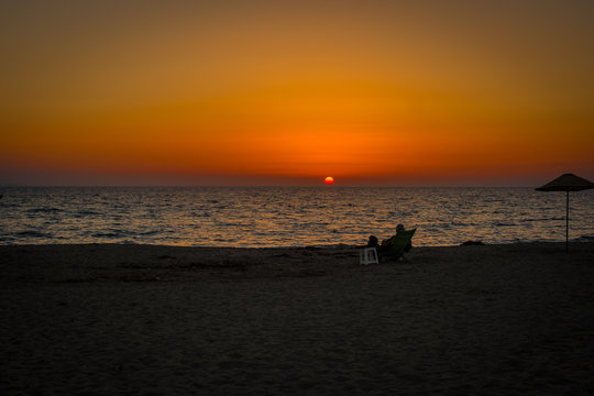 man sitting alone on the beach sunset © Emre