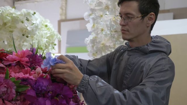Workers in uniform doing flower composition at manufacturing workshop