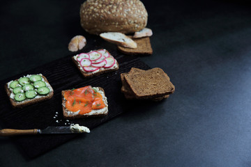 Sandwich with cereals bread smoked salmon beetroot and cucumber on dark marble background