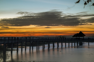 Fototapeta na wymiar A beautiful twilight on a wooden bridge stretching to the lake 