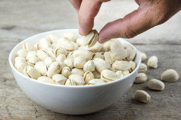 Hand picked Pistachio nuts in a cup on wooden background.