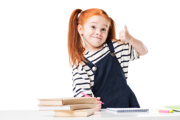 adorable smiling redhead schoolgirl drawing with felt tip pens and showing thumb up isolated on white