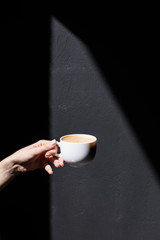 cropped view of person holding cup of coffee on black