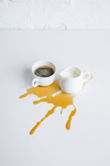 cup of coffee and milk jar with coffee stain on white tabletop
