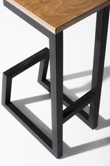 Studio shot of stylish barstool with wooden top and black metallic legs standing on white