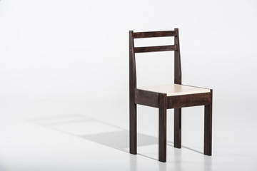 Classic dark wooden chair with white top standing on white floor in studio