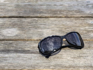 Black sunglasses on a wooden background. 