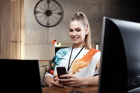 Blonde girl sitting at desk using mobilephone