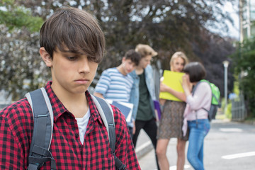 Fototapeta na wymiar Unhappy Boy Being Gossiped About By School Friends
