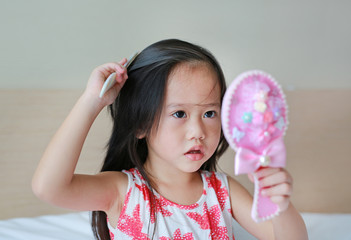 Happy Cute little girl combing her hair.