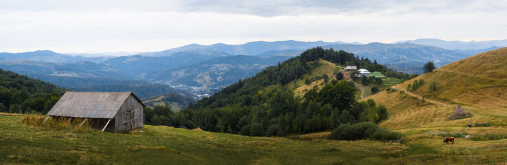 Nice panoramic view of low mountain range, valley and barn at foreground