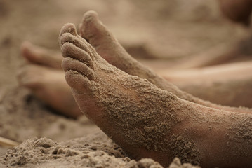 Feet of a small girl with sand on the beach