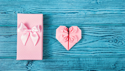 A gift box with a bow and a delicate pink heart made of paper. Romantic concept. Postcard heart of...