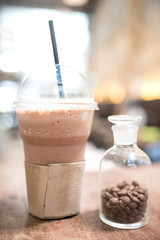 Ice coffee and roasted coffee beans in a jar on a wooden table.