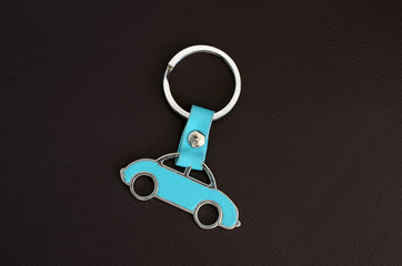 Key chain with cyan beetle car on dark leather pad as background