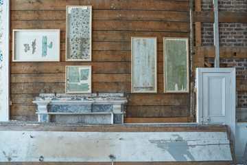 Restoration of room in a building showing examples of oak planks and red brick with a small white door and framed examples of previous wall coverings
