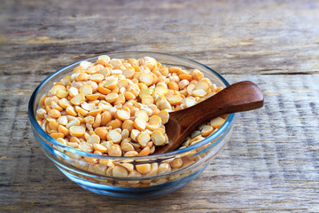 Dried peas in a glass bowl and a wooden spoon