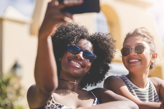 Two happy female friends taking selfie by smartphone