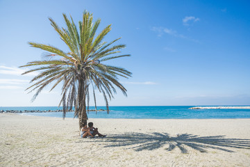 Two women relaxing at seaside under the palm