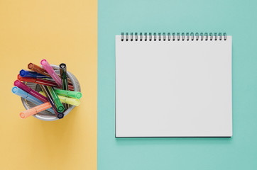 Office workplace minimal concept. Blank notebook, color pen box on yellow and green turquoise...