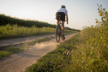 Naklejka premium Male in helmet and sportswear on his cyclocross bike, riding on the country roads 