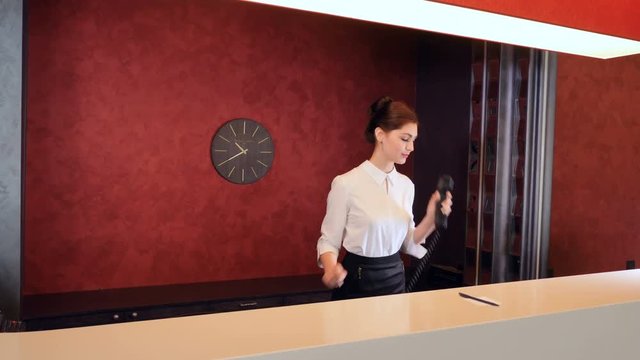Woman at hotel reception talking on the phone.