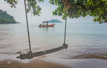 An ancient wooden swing set hung from a tree above a sandy beach, Chanthaburi, Thailand.