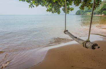 An ancient wooden swing set hung from a tree above a sandy beach, Chanthaburi, Thailand.
