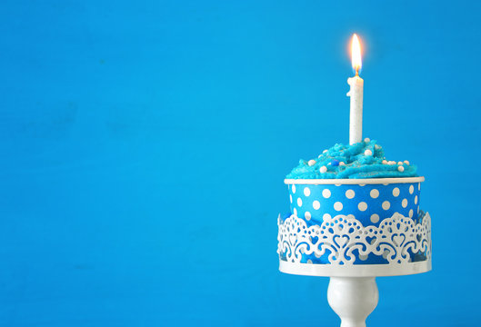 Birthday concept with cupcake and one candle on wooden table