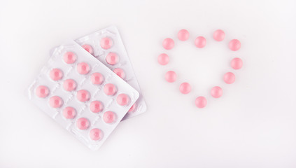 Pink tablets. Heart of pills. Pink tablets in a blister on a white background. Copy space