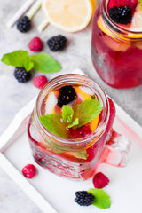 Summer Berry Drink. Lemonade with raspberry and blackberry with lemon, mint in mason jar on gray stone table background. Top view