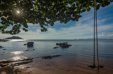 A wooden swing  hung from a tree above a sandy beach in the morning, Chanthaburi, Thailand.