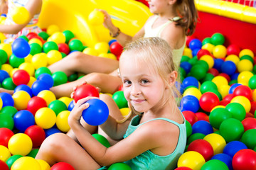 Fototapeta na wymiar Girl playing with multicolored plastic balls