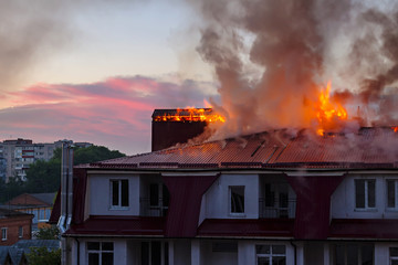 Burning fire flame with smoke on the apartment house roof in the city