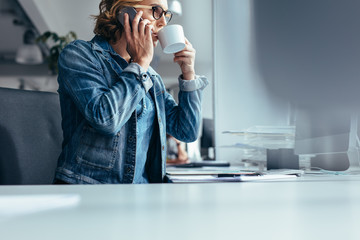 Young businesswoman making phone call and having coffee