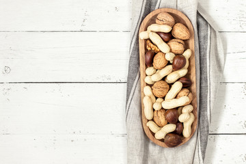 Nuts in a bowl on a white wooden background. Copy space