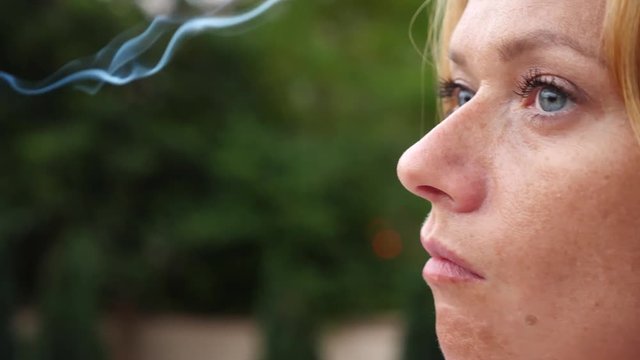 A woman smokes in the summer on the street thin cigarettes. 4 . Slow-motion