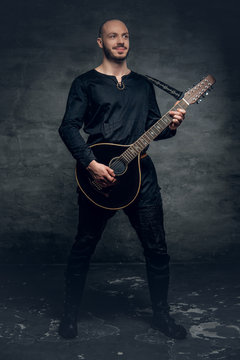 Studio portrait of a man in traditional Celtic clothes playing on mandolin.