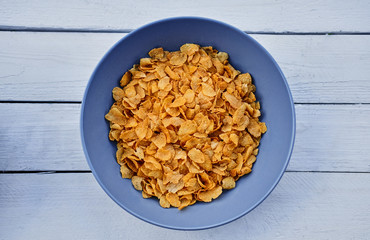 Corn flakes in a plate on a wooden desk.